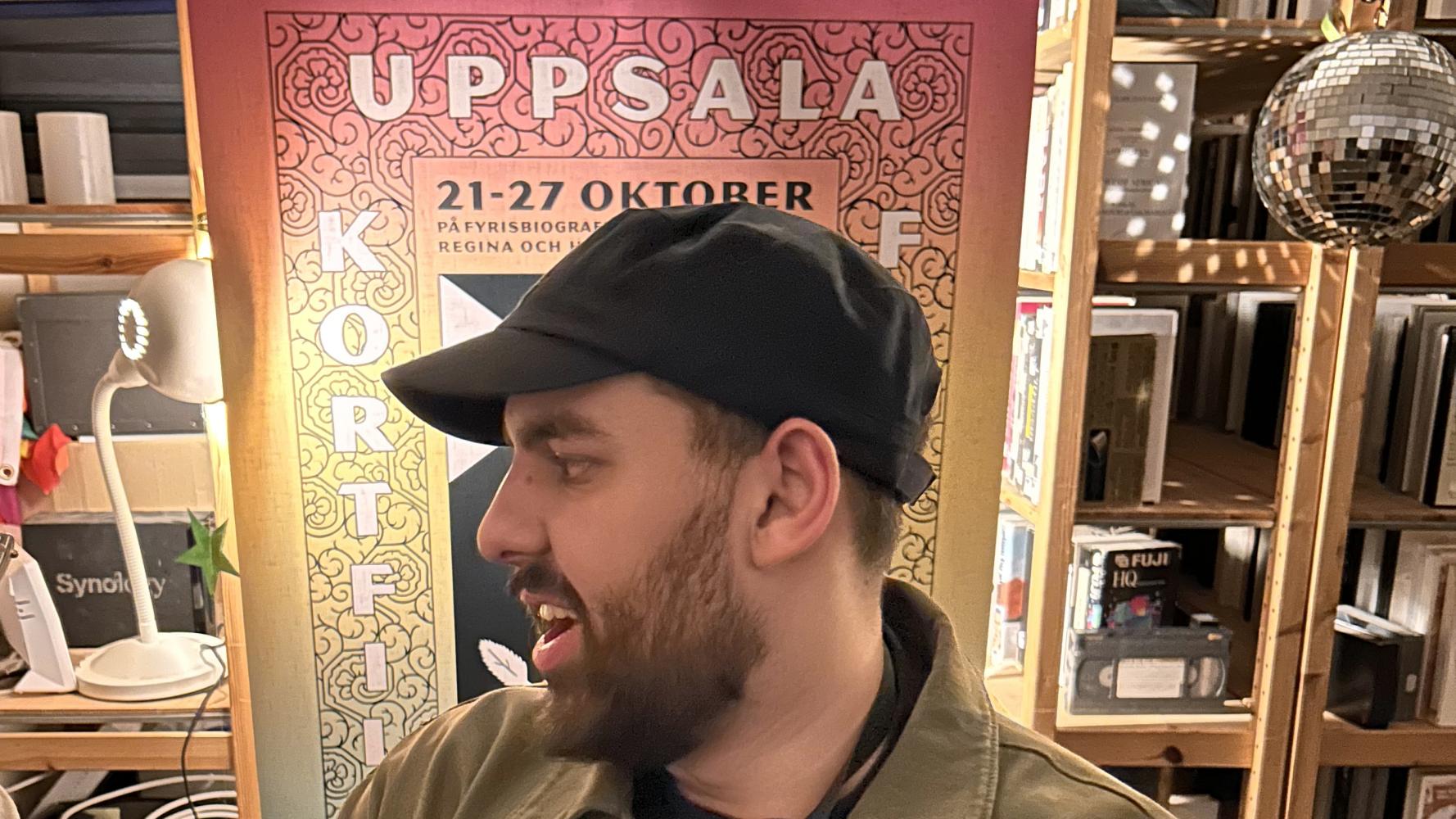 Man framför affisch för Uppsala Kortfilsfestival
