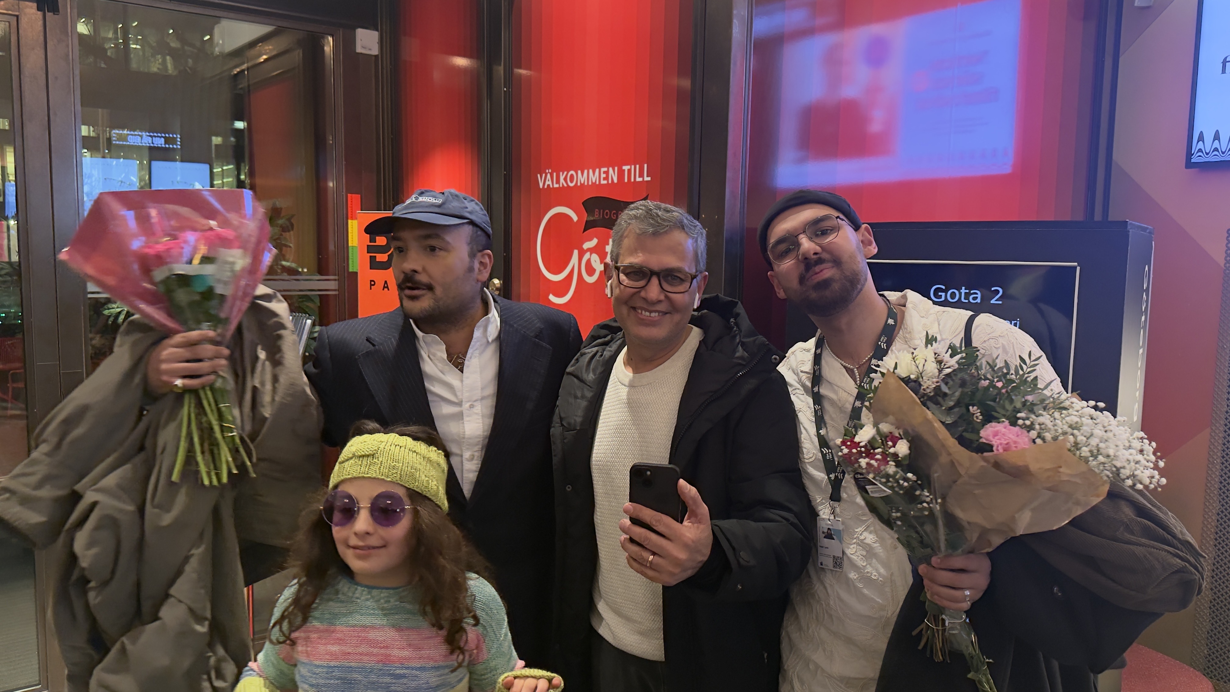 Tre män med blommor i händerna och ett barn med solglasögon