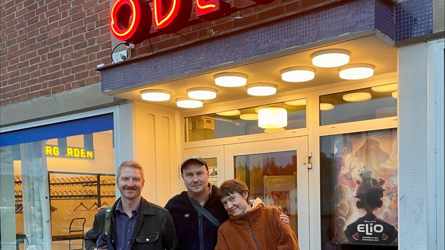 Tre personer poserar framför entrén till Odéon Bio
