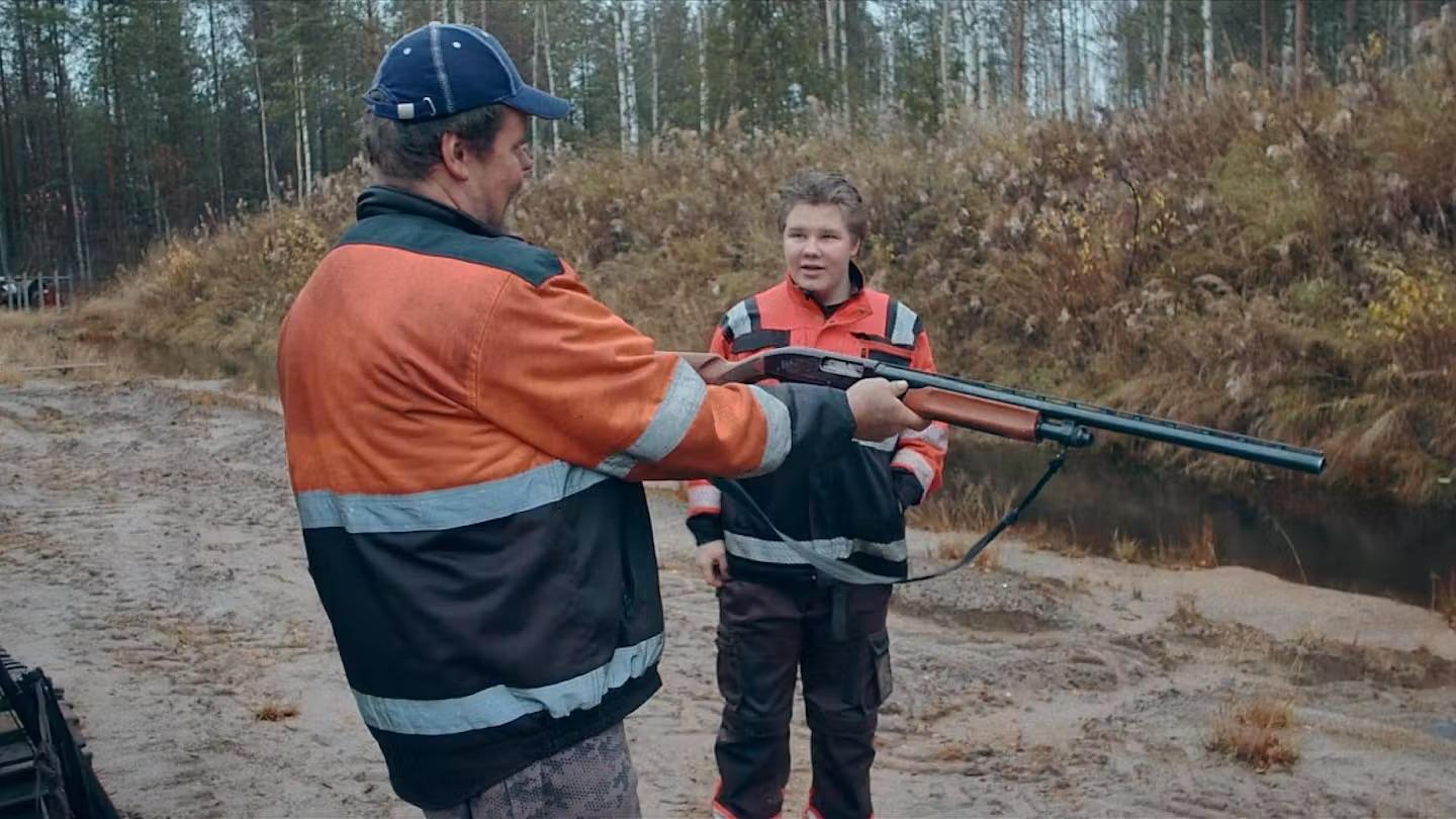 Äldre man visar yngre man gevär.