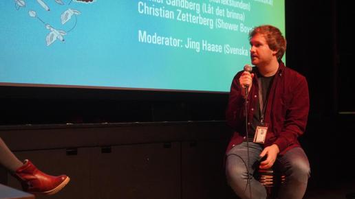 Man på barpall med mikrofon framför bioduk