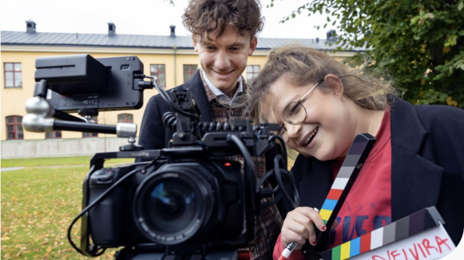 Kille och tjej bakom kameran med filmklappa