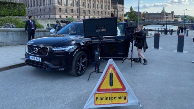 svart bil framför kungliga slotte och en skylt där det står filminspelning
